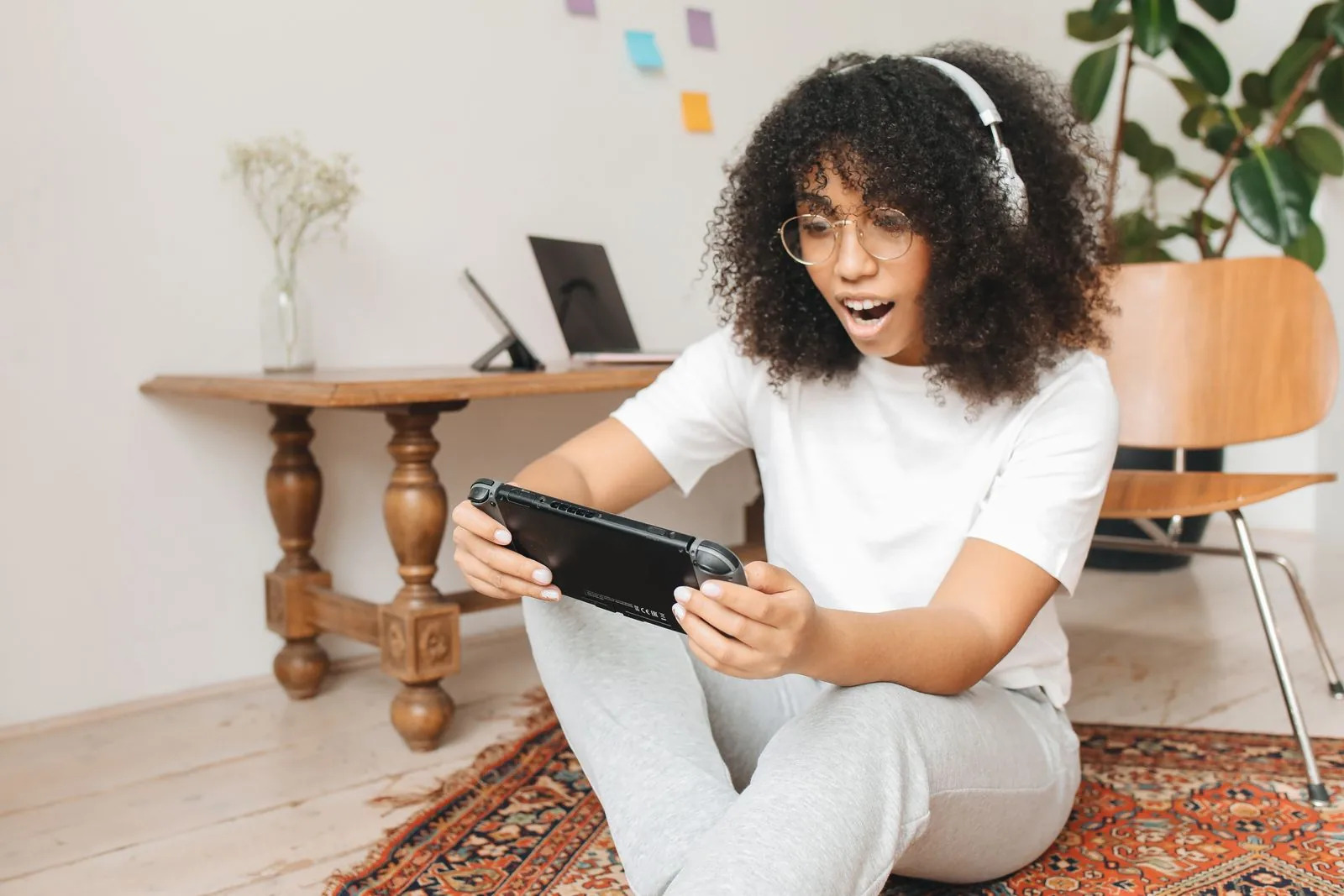 Woman sitting on the floor playing a Nintendo Switch in handheld mode, a typical cozy gaming setup