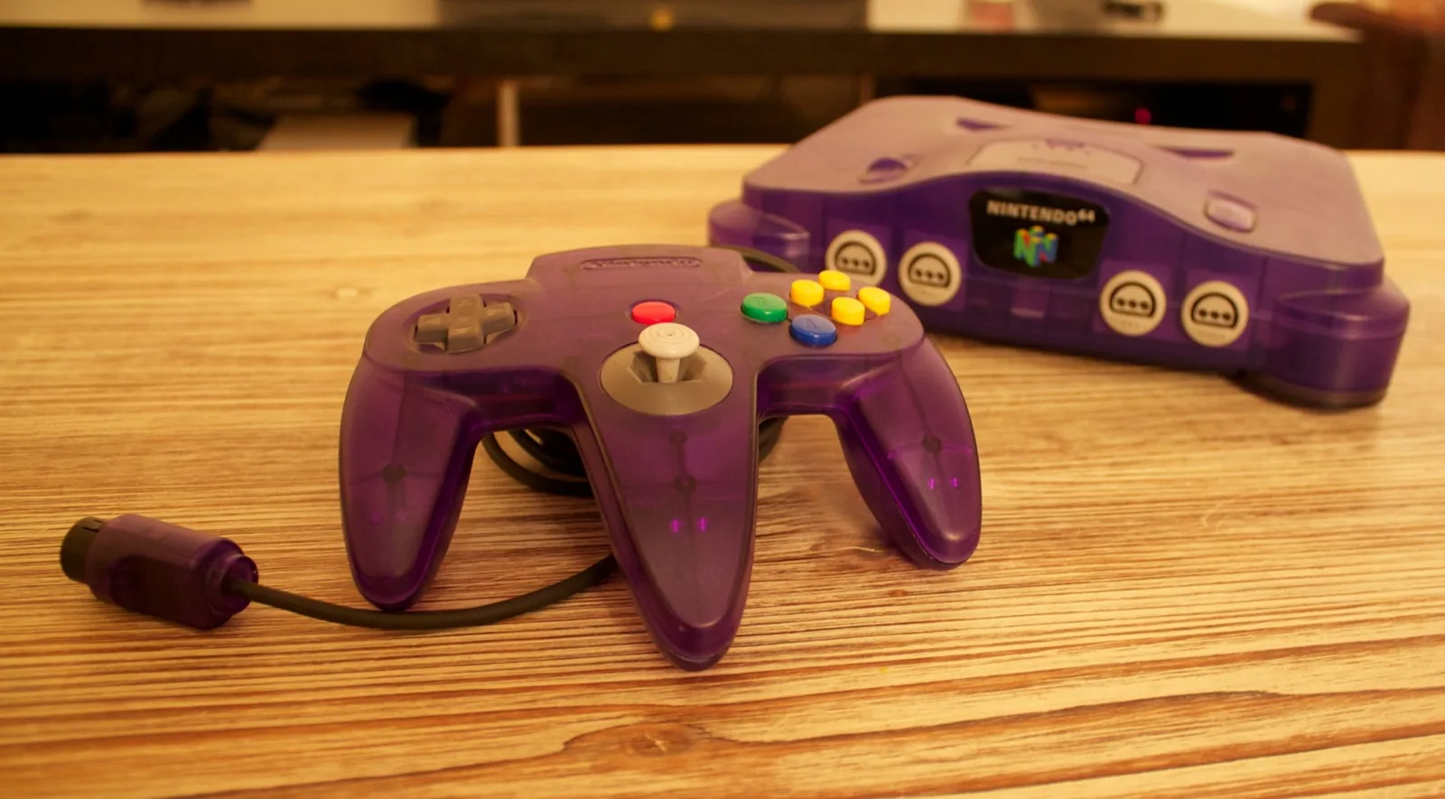 Purple Nintendo 64 console with its controller on a wooden table, the system behind the best N64 games